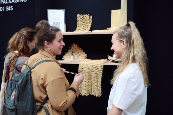 Des visiteurs et des exposants qui échangent sur un stand autour d'un produit packaging