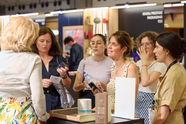 Des visiteurs et des exposants qui échangent sur un stand autour d'un produit packaging