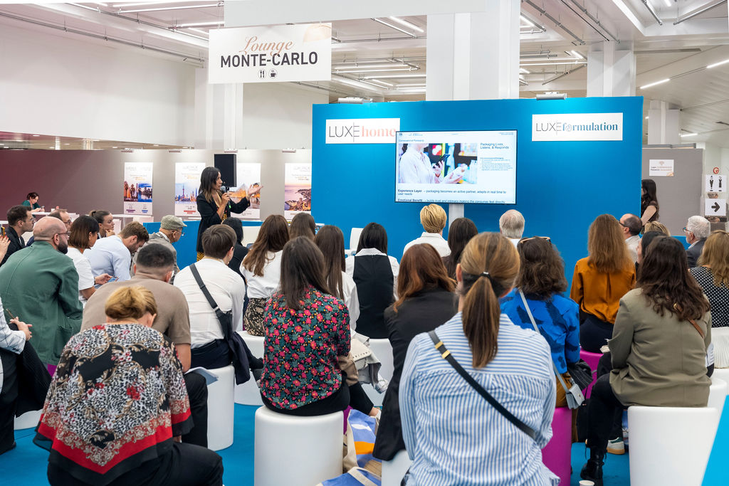 des visiteurs d'un salon qui écoutent un intervenant dans la zone des ateliers 