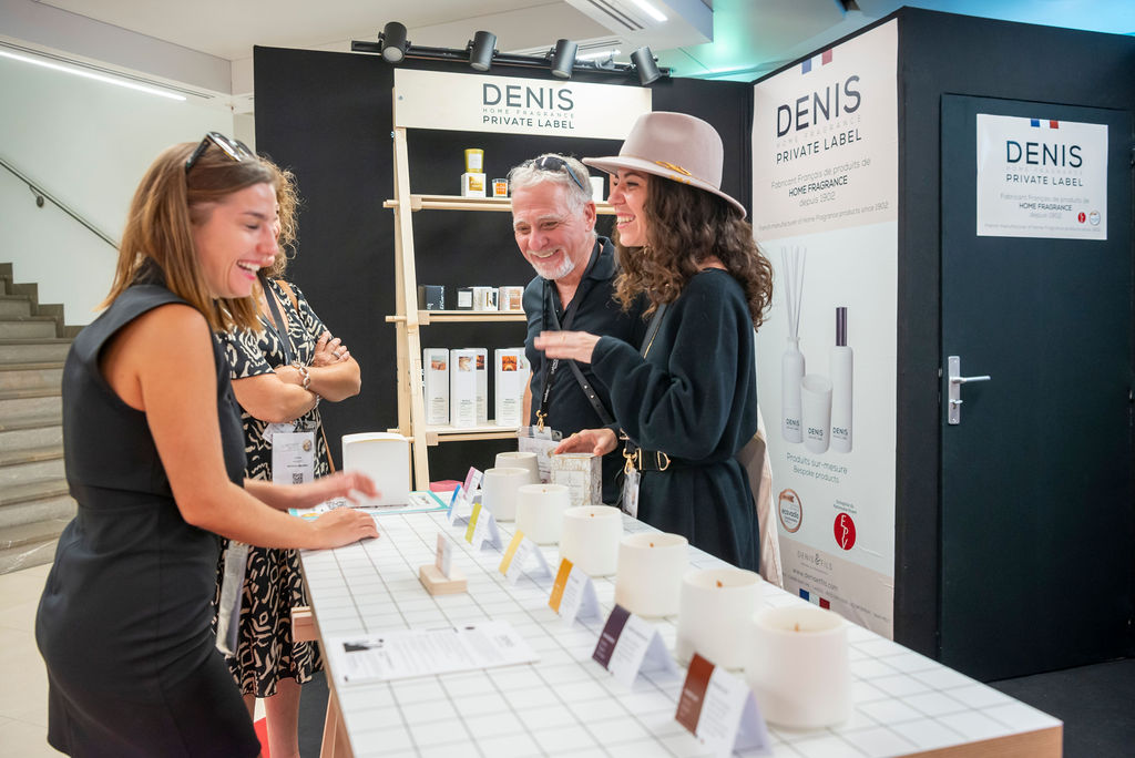 des personnes qui discutent sur un stand derrière des produits de maison et senteurs