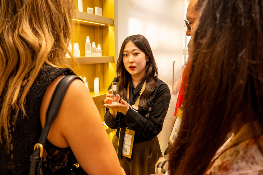 une femme est entrain de présenter un packaging de parfum à des clients