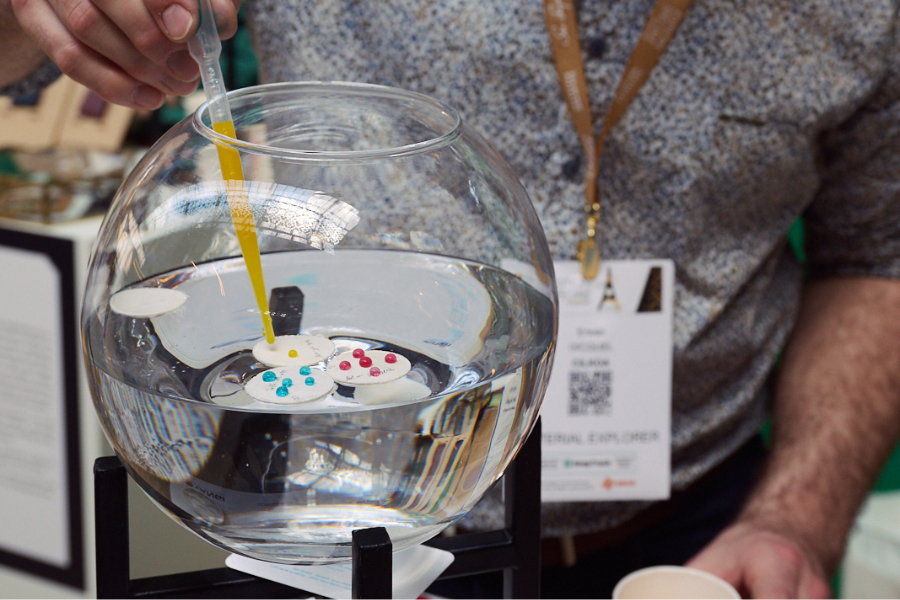 un vase de verre rempli d'eau avec des gouttes déposées par une pipette de colorants biodégradables et écoresponsables